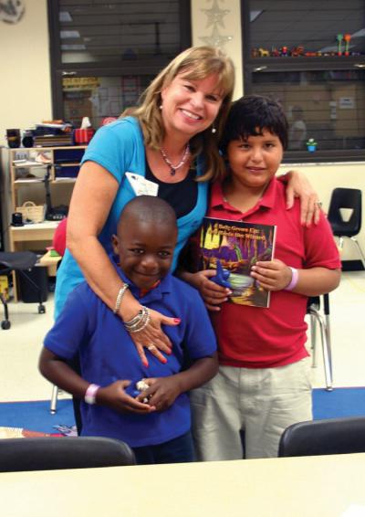 Caryn Hacker-Buechel shares her book about bullying with students Jaques Joseph and David Garay at Mike Davis Elementary School.